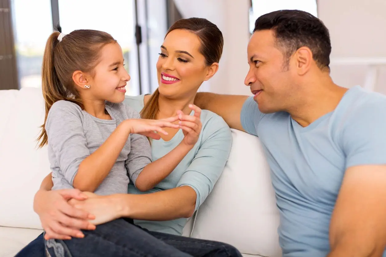 A man, woman, and a little girl sitting on a couch, enjoying each other's company.