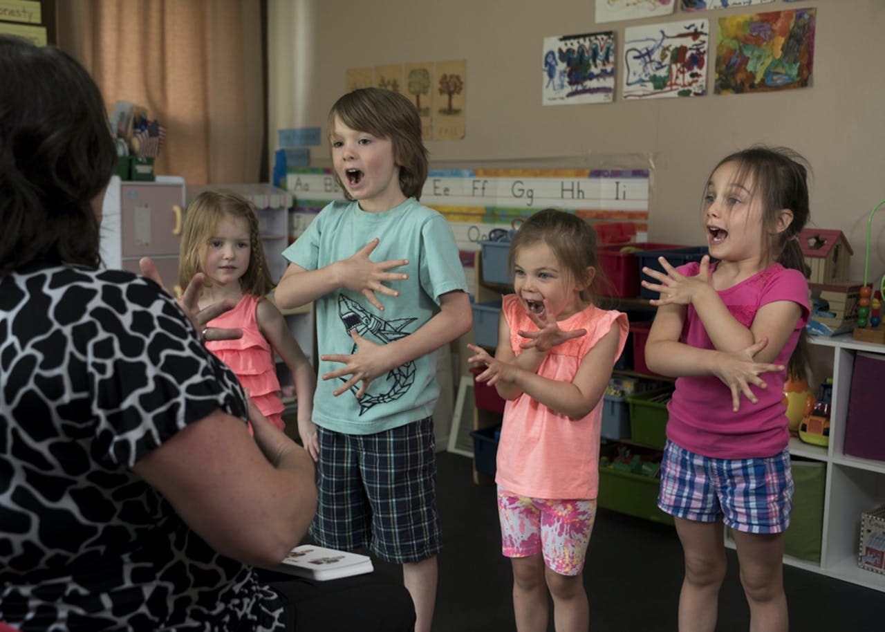 A classroom filled with children joyfully singing together. 1. Children singing in a classroom, creating a harmonious atmosphere. 2. A group of kids singing in a classroom, expressing their love for music. 3. A classroom scene with children happily singing, showcasing their musical talents.